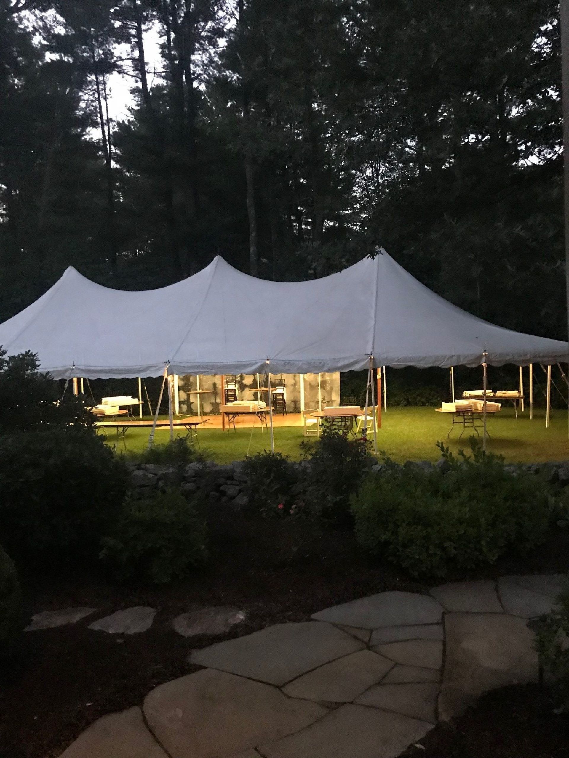 Photo of a wedding tent being setup on a lawn.