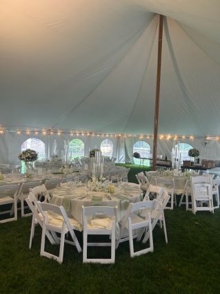 Elegant outdoor wedding reception with beautifully decorated tables and chairs under a canopy.