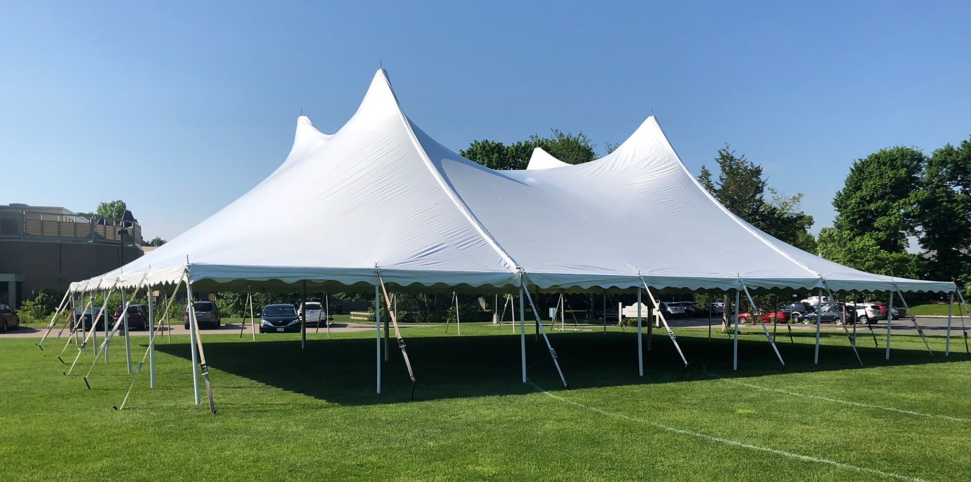 Elegant outdoor wedding setup with decorated chairs and floral arrangements under a clear blue sky.